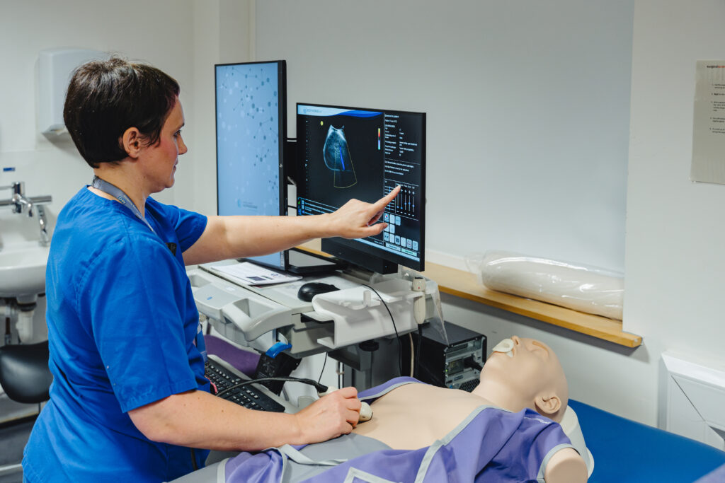 A sonographer using ultrasound simulation equipment on a mannequin