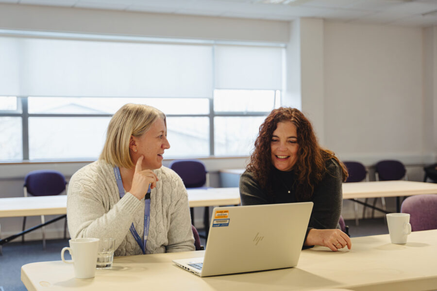 Two women talking in front of a laptop